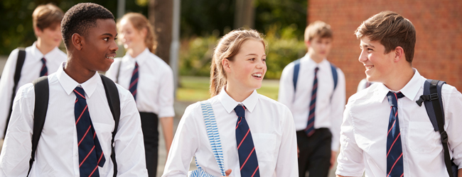 Three young students walking and talking together wearing a student uniform