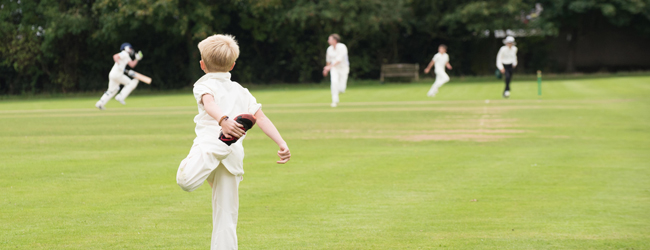 A young boy is preparing for a cricket game on a sports field